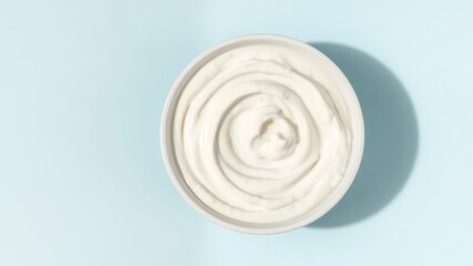 Creamy delight Overhead view of white swirl inside ceramic bowl set against a tranquil light blue backdrop