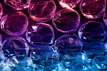 Macro view of bubble wrap in vibrant pink purple and blue lighting showcasing translucent texture