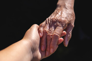 Obraz premium Touching Hands of Two Generations on a Black Background