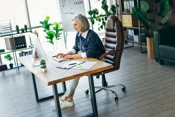 Confident mature businesswoman working in a modern office environment surrounded by indoor plants and elegant decor