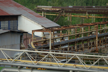 A large building featuring a striking red roof and an industrial conveyor belt positioned right in...