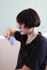Young person brushing bowl cut hairstyle with lavender comb