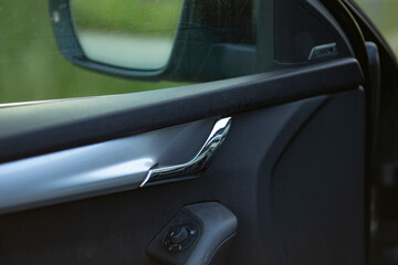 This image features a closeup view of a cars door handle alongside its rear view mirror, showcasing intricate details and craftsmanship