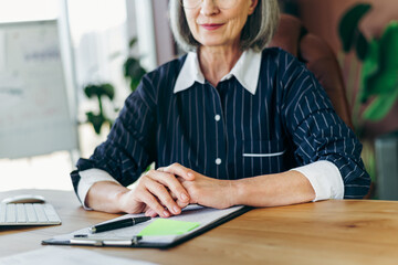 Elegant mature businesswoman at workspace exhibiting confidence and professionalism during office...