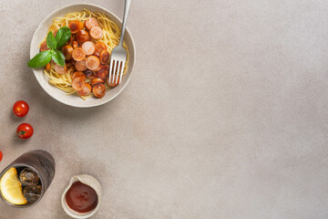 Spaghetti with sausage and tomato sauce on beige background