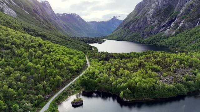 Aerial view of Eikesdal valley with winding road, serene lake, and forested mountains in Norway