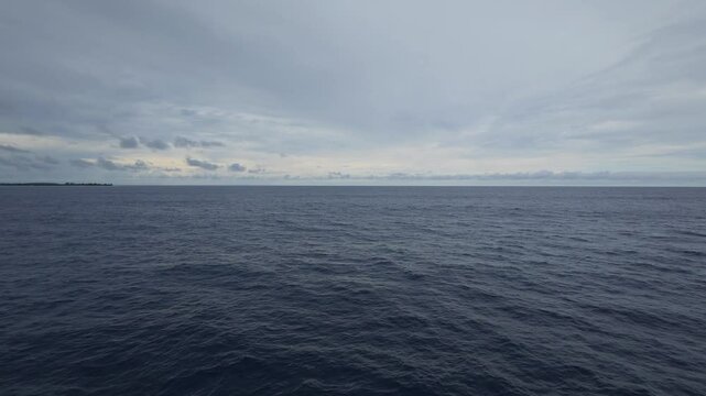 Drone footage of calm ocean under a cloudy sky, fading into the horizon with soft light and waves - Powered by Adobe
