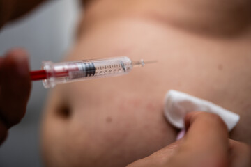 Doctor injecting insulin with syringe to patient's belly
