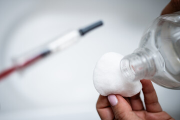 Nurse pouring disinfectant on cotton ball for injection preparation