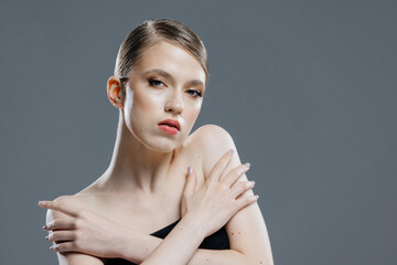 Young woman with perfectly smooth skin on gray isolated background. Female facial plastic surgery, dermatology, spa and cosmetology.