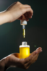 Close-up mockup of glass bottle with dropper in female hand. Amber container with cosmetic product,...