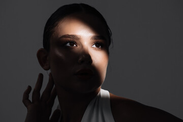 Close-up of a beautiful woman with glowing skin posing in a studio in dim lighting. Ideal for...