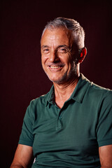 Smiling Man With Gray Hair in a Green Polo Shirt Against Dark Background