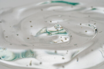 A background with the texture of a serum or gel with collagen and shimmering particles. Close-up, macro photography.