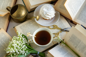 A cup of tea and a bouquet of lilies of the valley, books on a spring morning.