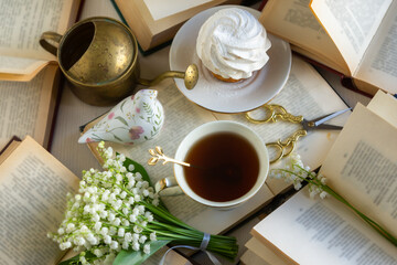 A cup of tea and a bouquet of lilies of the valley, books on a spring morning.