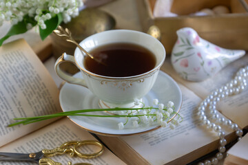 A cup of tea and a bouquet of lilies of the valley, books on a spring morning.
