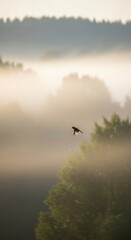 Fototapeta premium Serene morning mist with bird in flight over lush greenery