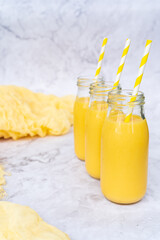 Fresh yellow tropical smoothies in a glass bottles with a straws.