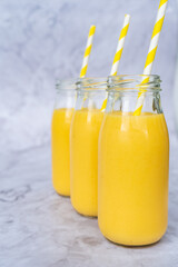 Fresh yellow tropical smoothies in a glass bottles with a straws.