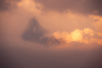 A breathtaking morning view of Annapurna South when the peak is bathing in sun light with clouds in great Himalayas in Nepal.