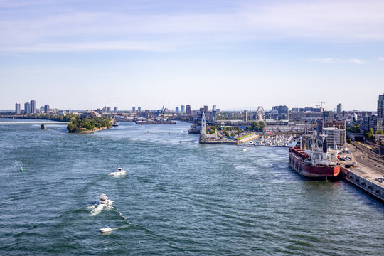 A view of Montreal with the skyline in the distance, the St. Lawrence River in the foreground, and several boats on the water.