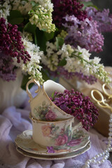 A bouquet of lilacs on the table and a cup of tea.