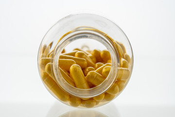 A jar with pills inside lies on a white background. Hyaluronic acid, collagen, vitamins or barberry...
