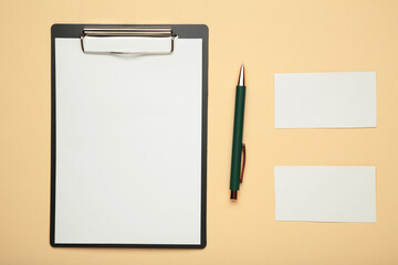 Clipboard with blank paper sheet mockup and stationery on beige background. Workspace for education.