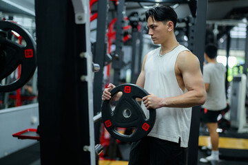 Young sportsman holding weight plate in modern gym