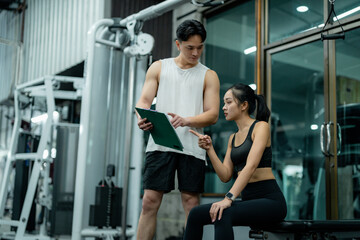 Personal trainer showing training schedule to sportswoman in gym
