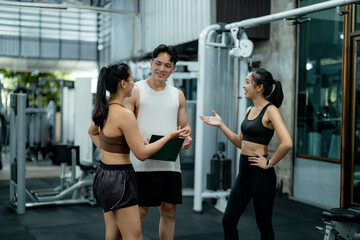 Personal trainers discussing workout routine with client in gym