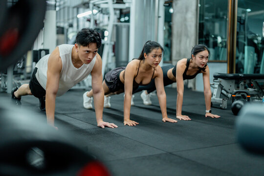Determined athletes performing push-ups together in modern gym
