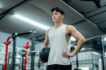 Young Sportsman Holding Medicine Ball Posing in Gym