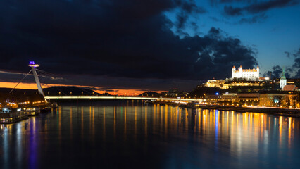 Bratislavas night view with illuminated landmarks and river reflections