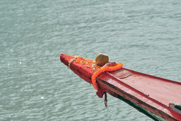 Wooden bow of a country boat, decorated with floral garlands & coconut. This practice is usually...