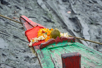 Wooden bow of a country boat, decorated with floral garlands & coconut. This practice is usually...