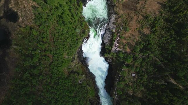 Gaustafallet waterfall flowing through vegetations next to the E14 highway at sunset