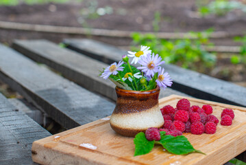 vase with flowers and a handful of red raspberries. High quality photo
