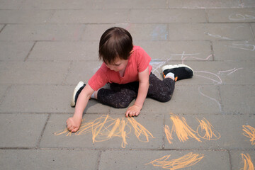 Boy drawing on pavement with colorful chalk. Child creating art outdoors enjoying summer day. Kid activity and creative play. A child aged 3 years