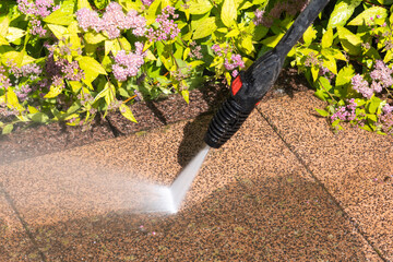 Close -up of cleaning dirty terrace with pressure washer. Visible before-and-after effect when...