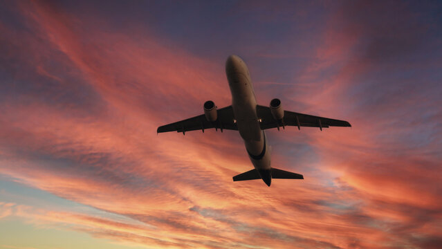 Airplane in the sky. Airplane in flight at sunset or evening sky. Commercial airliner silhouette in the colorful evening or night moon skies. Aircraft symbol of travel adventure global connectivity.