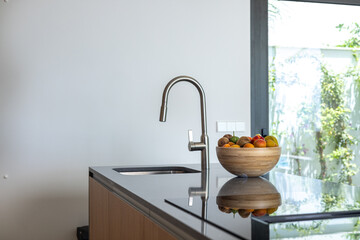 Modern kitchen sink with chrome faucet and fruit bowl on polished counter top.