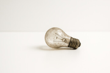 Old Dusty Lightbulb on Clean White Floor – Concept of Discarded Ideas