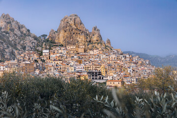Town with many houses on hillside and rocky cliff on sunny day, Gagliano Castelferrato, Sicily, Italy