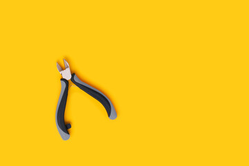 Wire cutters on a yellow background. Place for text.