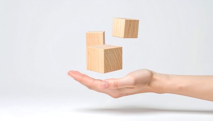 Hand balancing wooden blocks on white.