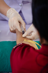 Soft focus on the hands of the doctor drawing a blood sample from the arm for blood test finds in hospital.