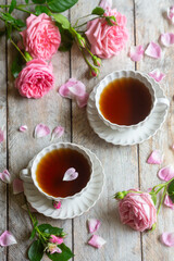 A cup of aromatic tea, a book and a rose on the table.