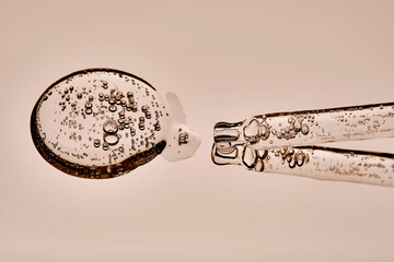 The texture of the serum and the pipette on a beige background.